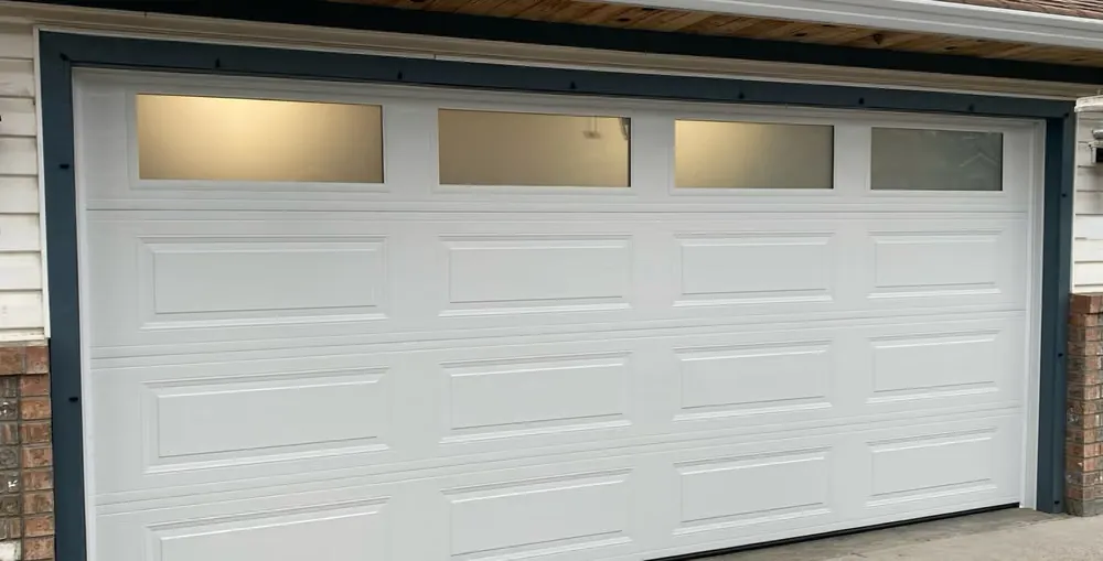 The same opening with a white double garage door, long raised panels and four frosted windows