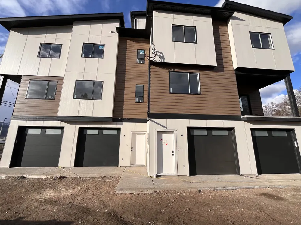 A three-storey modern home with four dark garage doors at street level