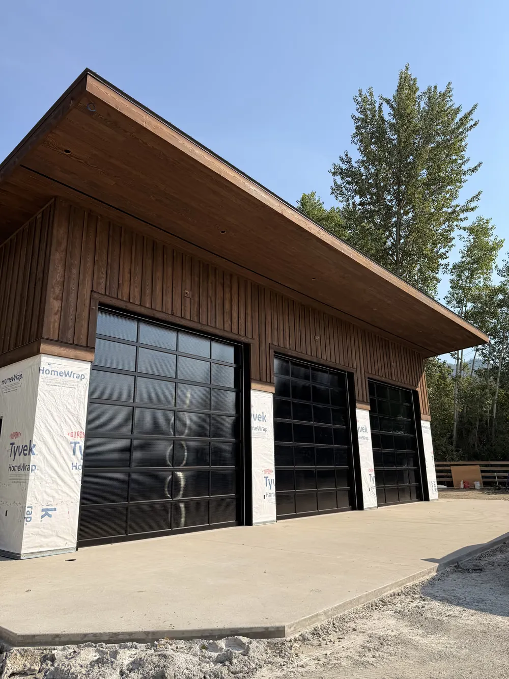 A wall of full-view glass garage doors along the side of a new build