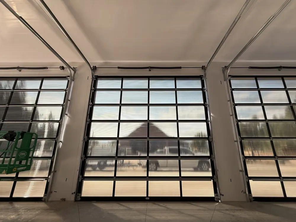 Full-view glass garage doors seen from inside a bright new shop