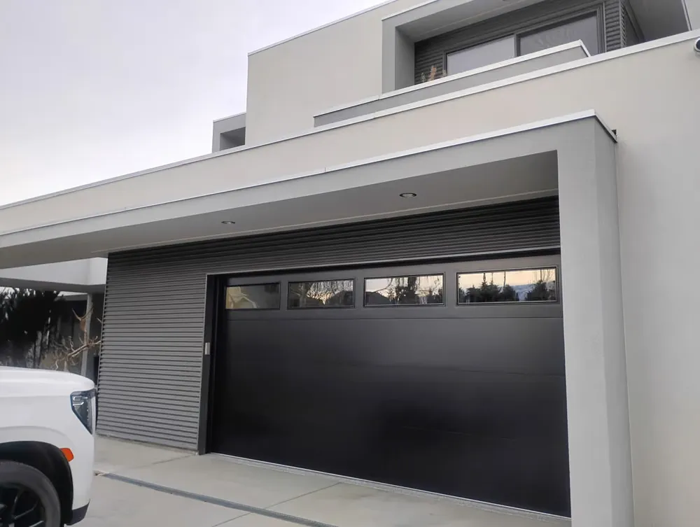 A dark garage door with narrow windows on a contemporary grey home