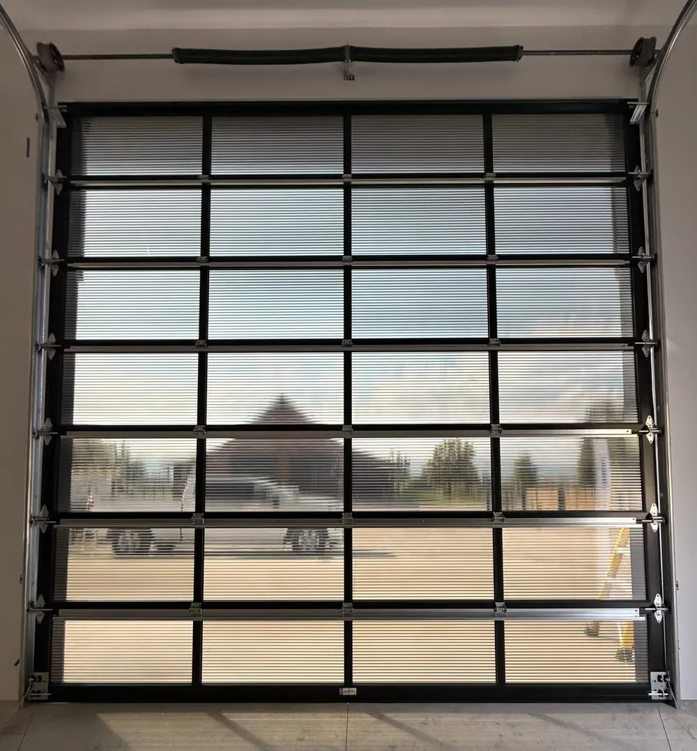 A full-view glass garage door filling the end wall of a new shop, the yard visible through its panels