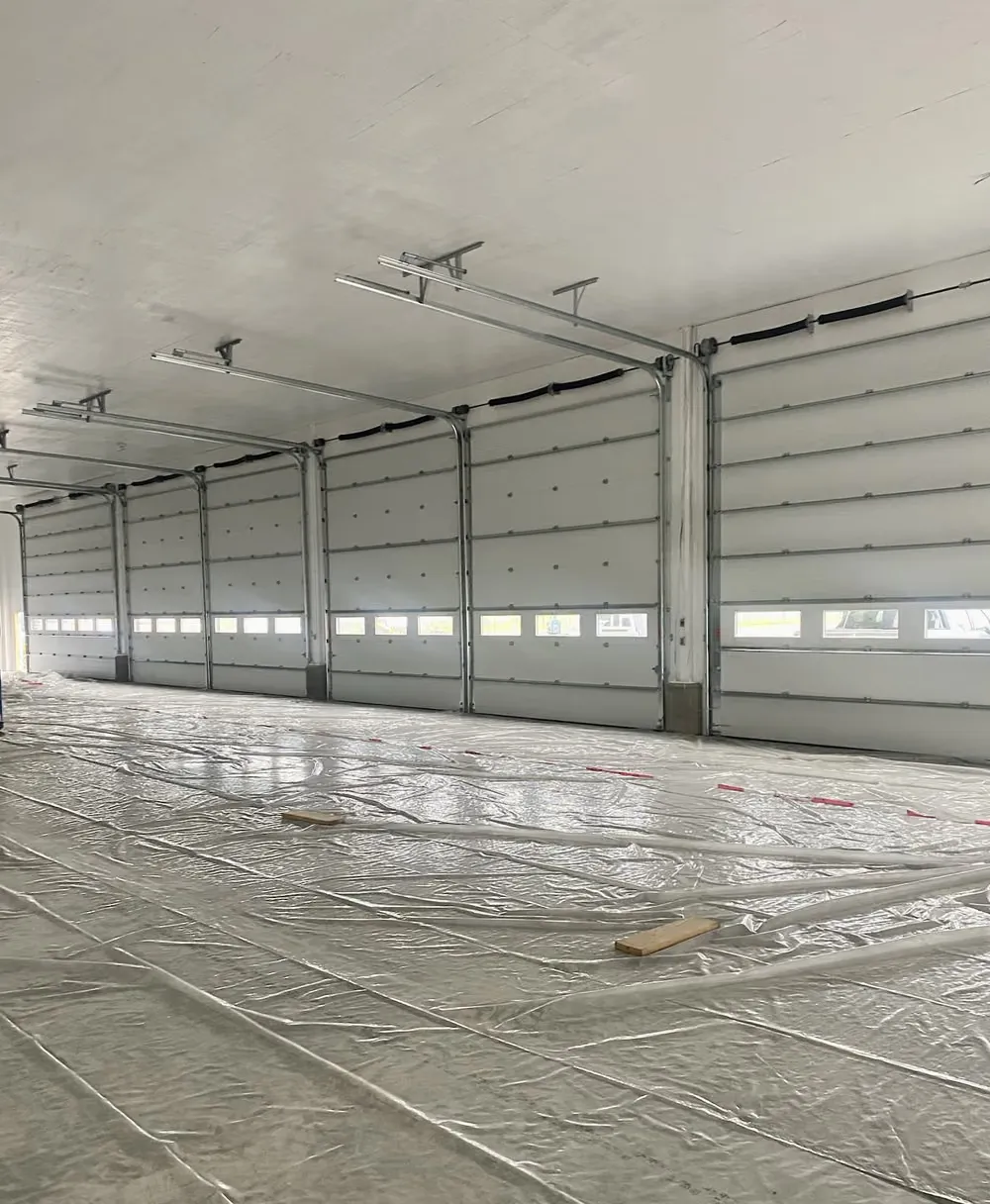 A row of insulated overhead doors with window panels inside a long commercial building