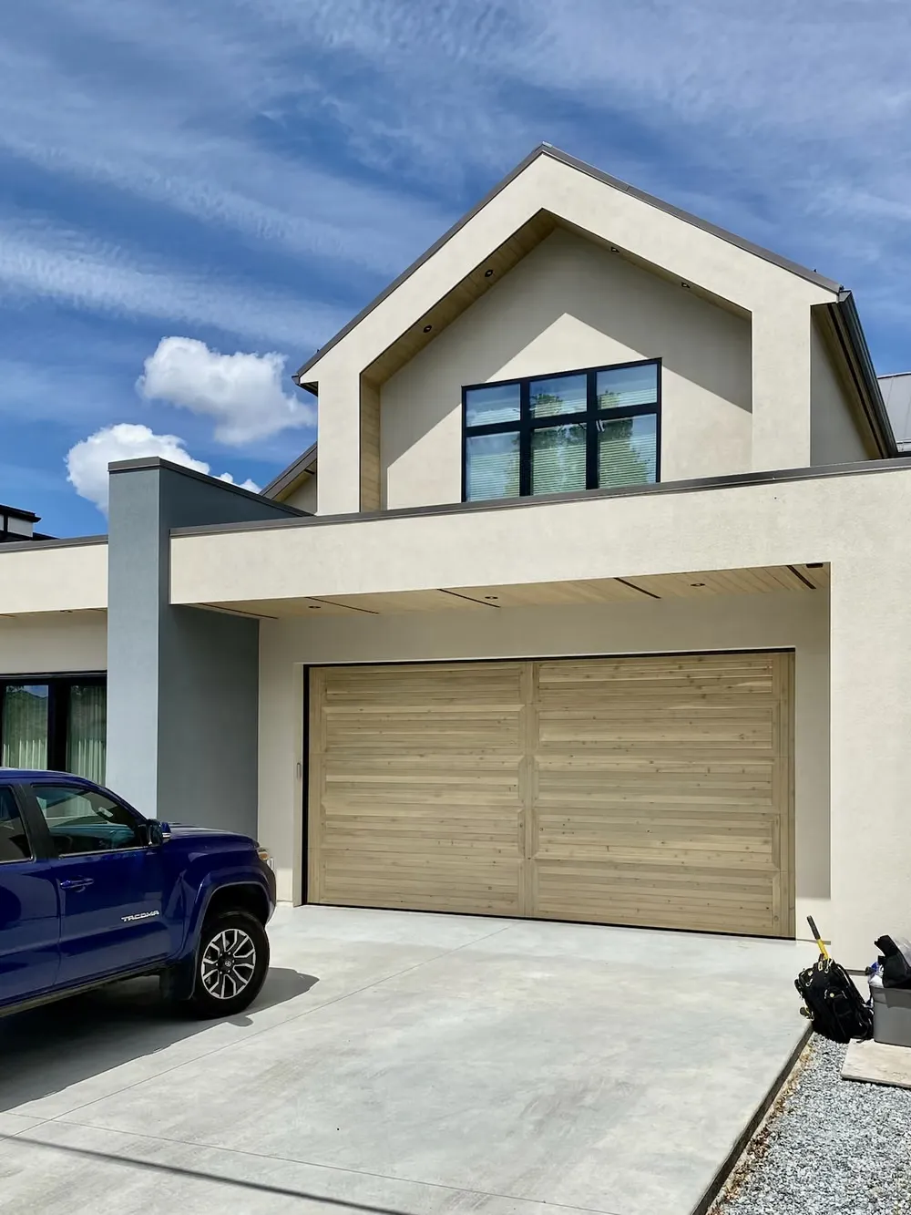 A wood-look garage door on a stucco home with a peaked gable and a truck in the driveway
