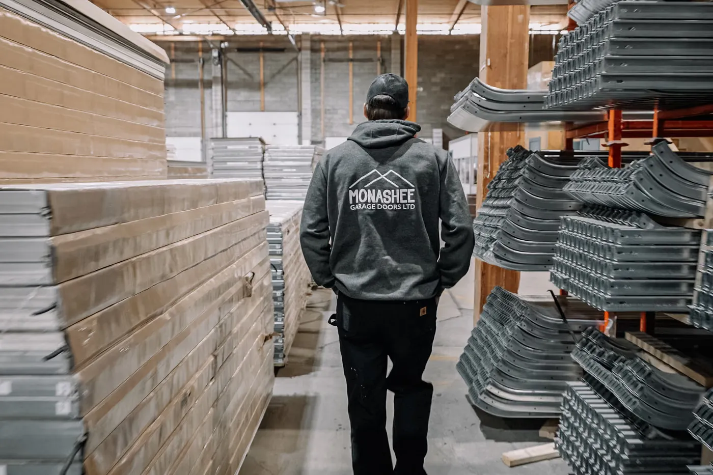 Jackson from Monashee Garage Doors walking through racks of door sections at the Steel-Craft warehouse in Kelowna